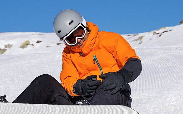 Skifahrer sitzt im Schnee und hält sich am Bein